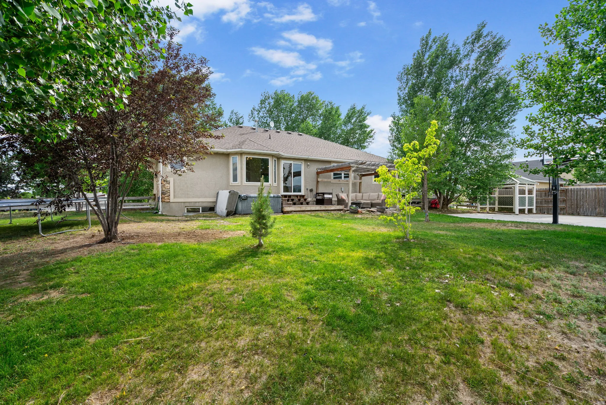 Back of house with a fenced backyard, a trampoline, and a patio