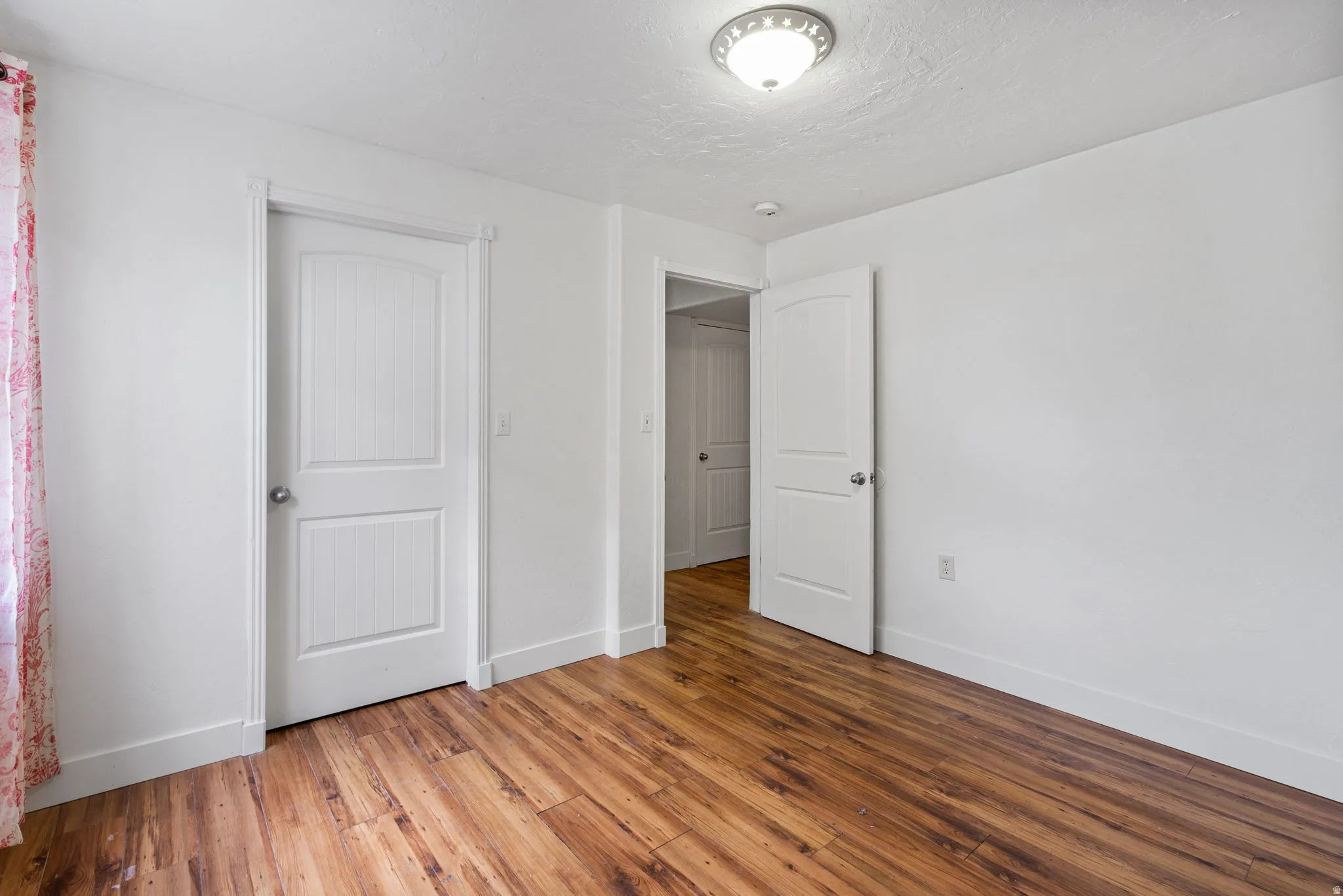 Unfurnished bedroom with light wood-style flooring and a textured ceiling