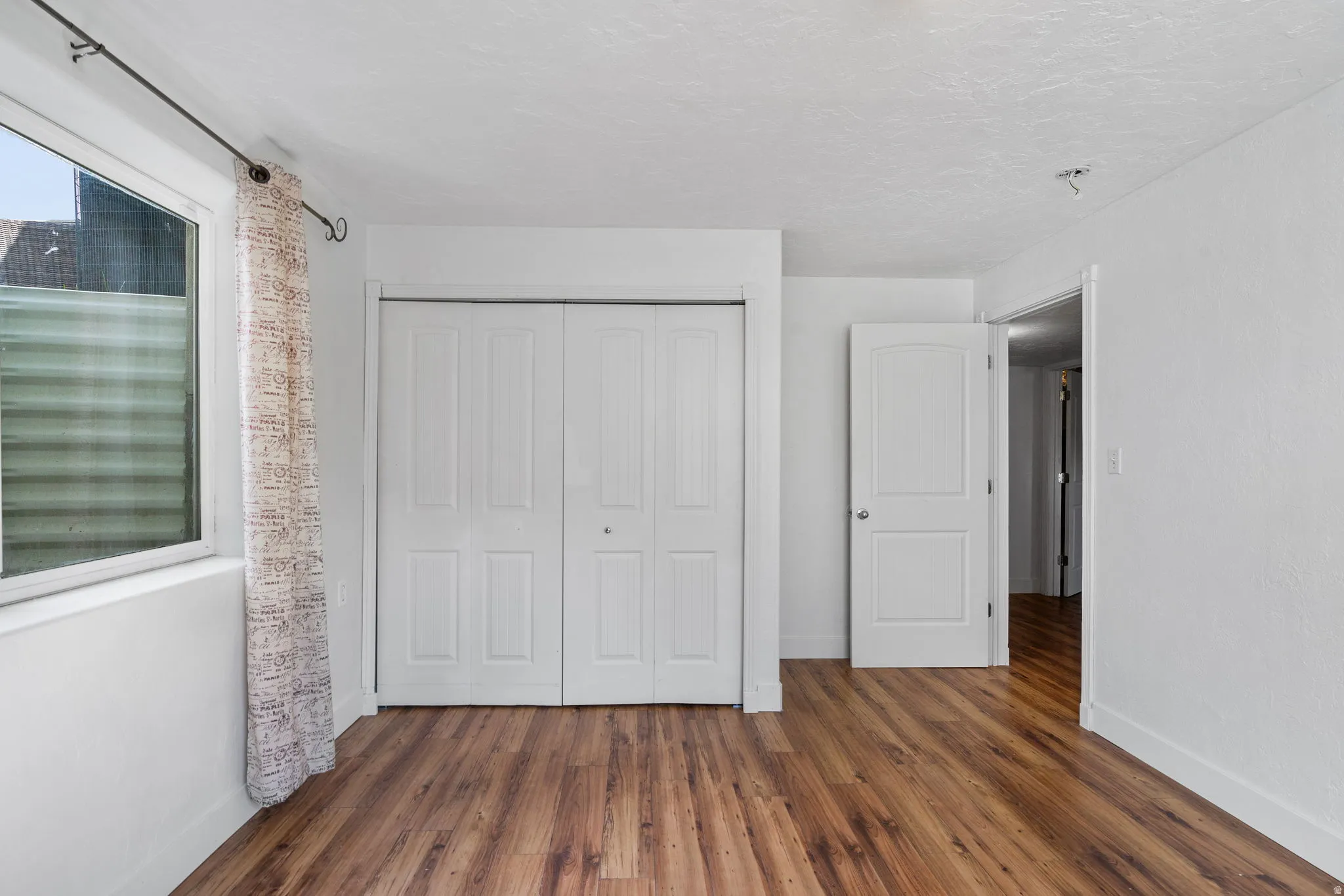 Unfurnished bedroom with dark wood-style floors, a closet, and a textured ceiling