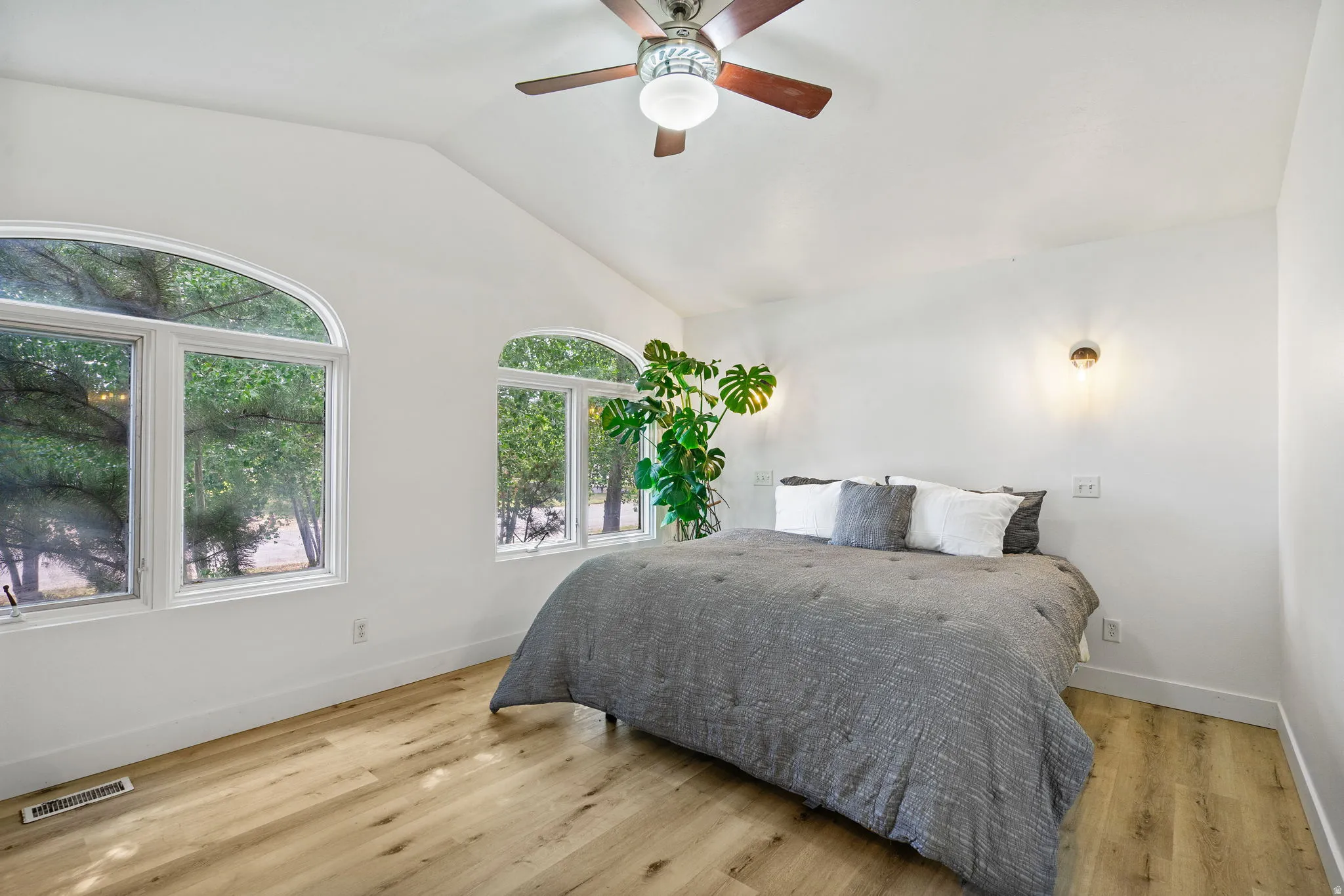Primary Bedroom featuring vaulted ceiling, light wood-type flooring, and a ceiling fan