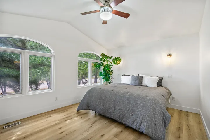 Primary Bedroom featuring vaulted ceiling, light wood-type flooring, and a ceiling fan