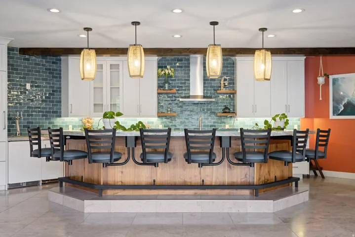 Kitchen with white cabinets, a breakfast bar, tasteful backsplash, and beamed ceiling
