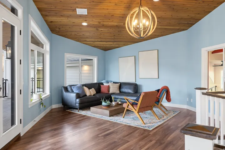 Living room featuring a vaulted wood ceiling, dark wood-type flooring, and hanging lights