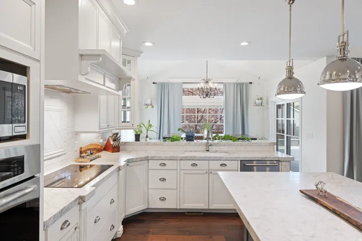 Kitchen with stainless steel appliances, white cabinetry, glass insert cabinets, dark wood-type flooring, and vaulted ceiling