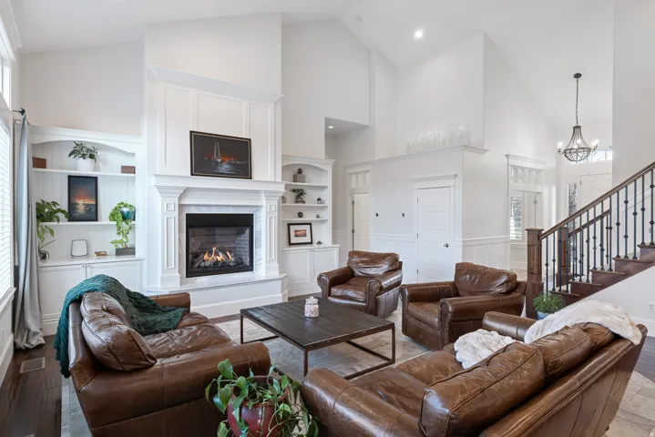 Living room featuring wood-type flooring, built in features, lofted ceiling, a glass covered fireplace, and plenty of natural light