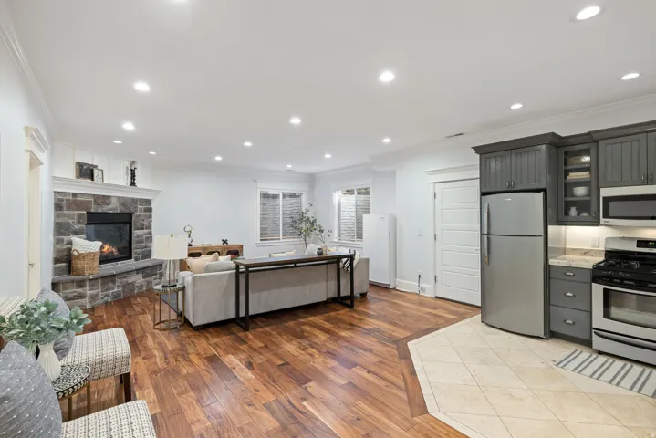 Kitchen with crown molding, open floor plan, stainless steel appliances, light wood-type flooring, and glass fronted cabinets