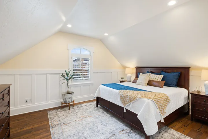 Bedroom featuring wainscoting, a decorative wall, dark wood-style flooring, and recessed lighting