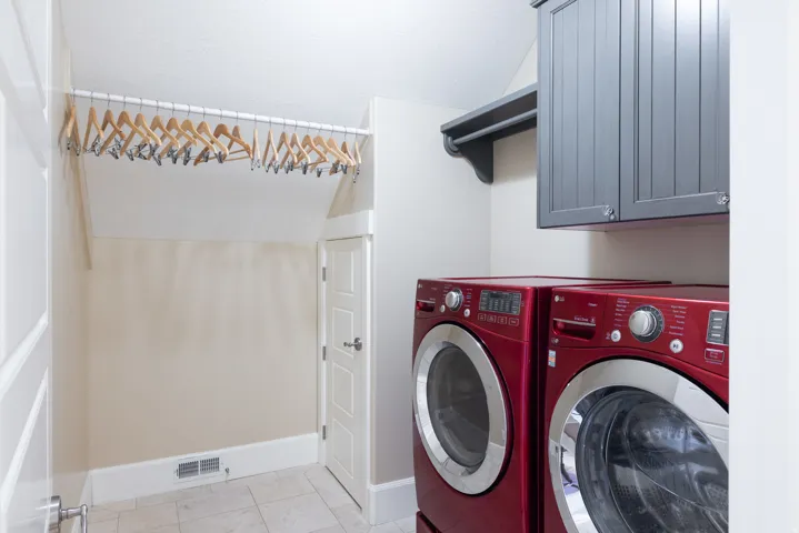 Laundry room with independent washer and dryer, light tile patterned floors, and cabinet space