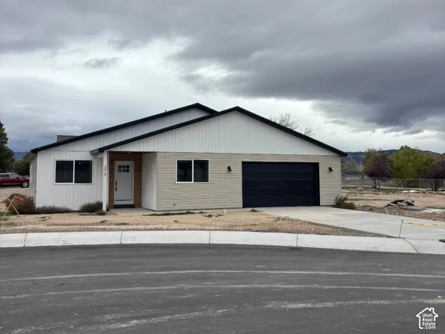 Contemporary exterior featuring vertical and horizontal siding, a two-car garage, concrete driveway, and mountain backdrop