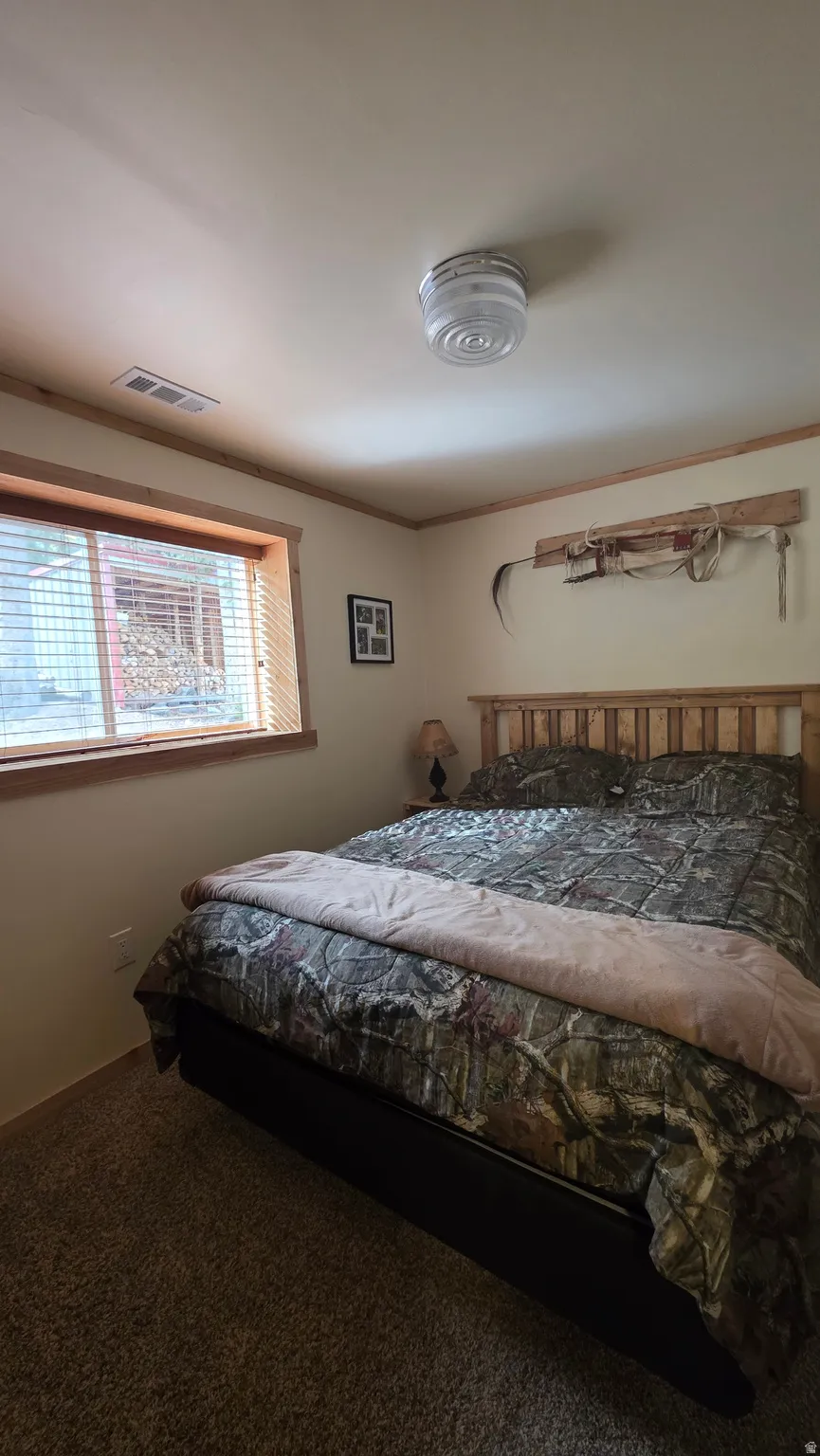 Carpeted bedroom with ornamental molding and baseboards
