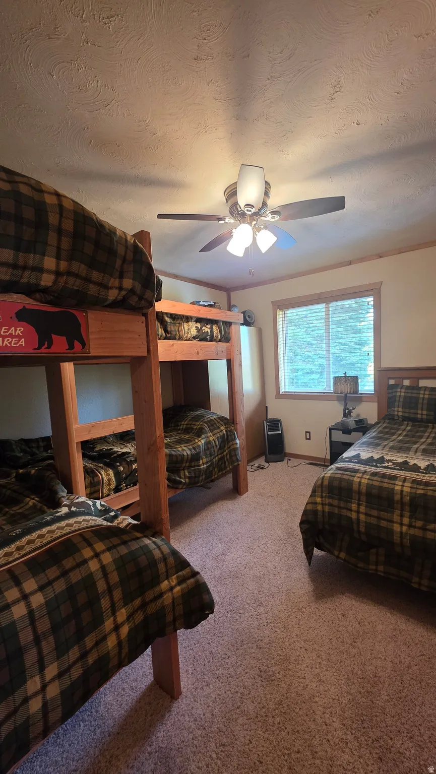 Bedroom featuring a textured ceiling, light carpet, and a ceiling fan