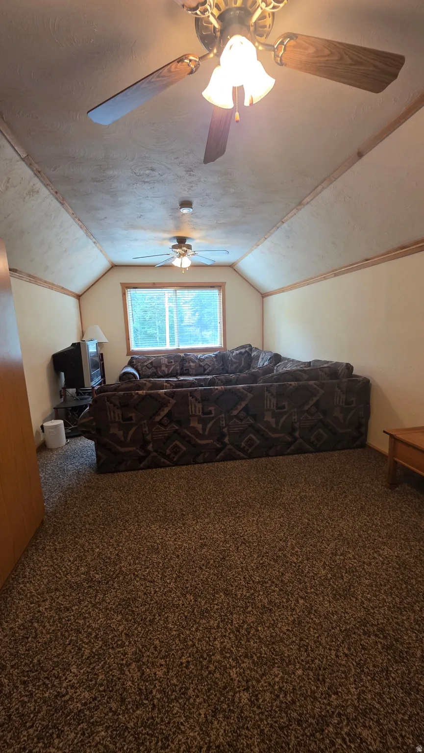 Carpeted bedroom with ceiling fan and a textured ceiling