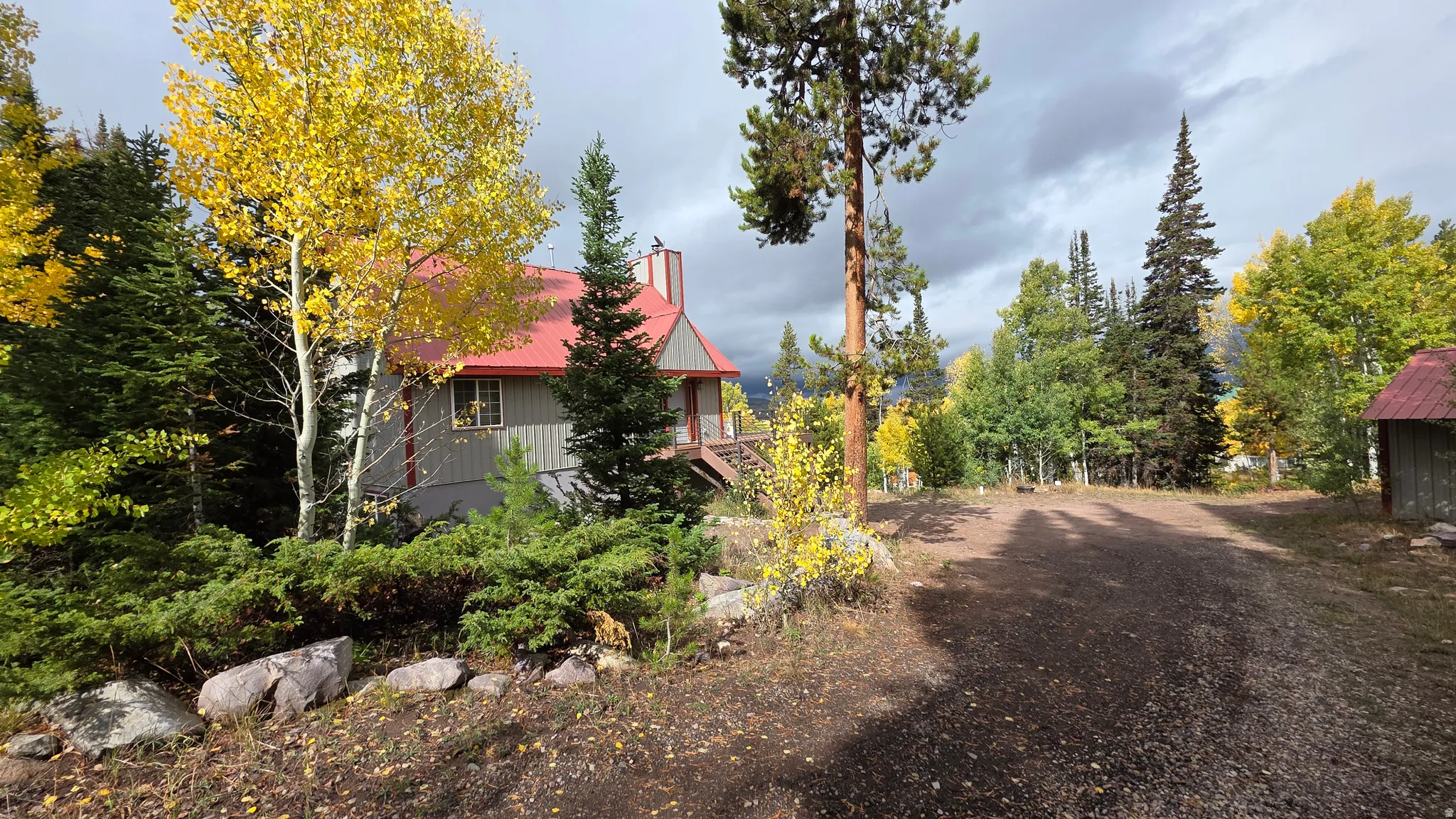 View of home's exterior with a metal roof, a chimney, and view of scattered trees