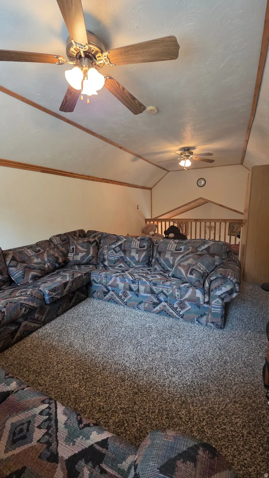 Carpeted bedroom featuring vaulted ceiling and ceiling fan