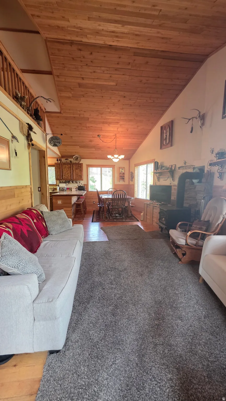 Living area with a vaulted wooden ceiling, wood finished floors, and wood walls