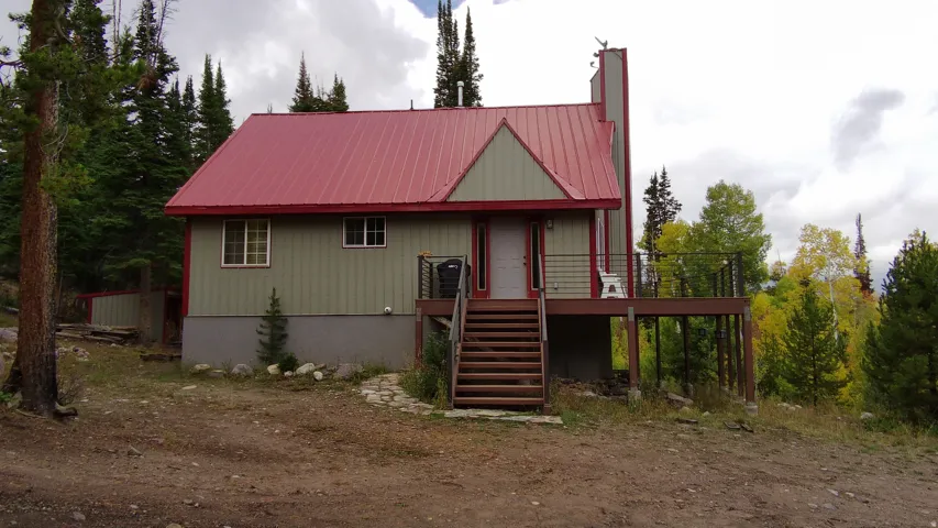 Rear view of house with a metal roof, a deck, and a chimney