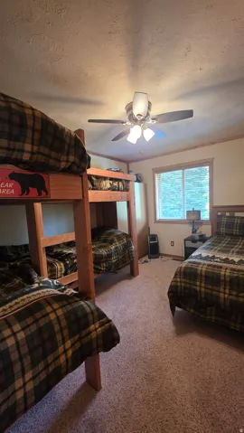 Bedroom featuring a textured ceiling, light carpet, and a ceiling fan
