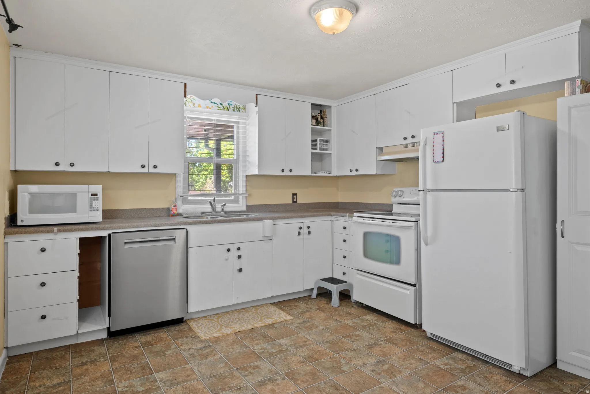 Kitchen with white appliances, white cabinets, open shelves, stone finish floors, and light countertops