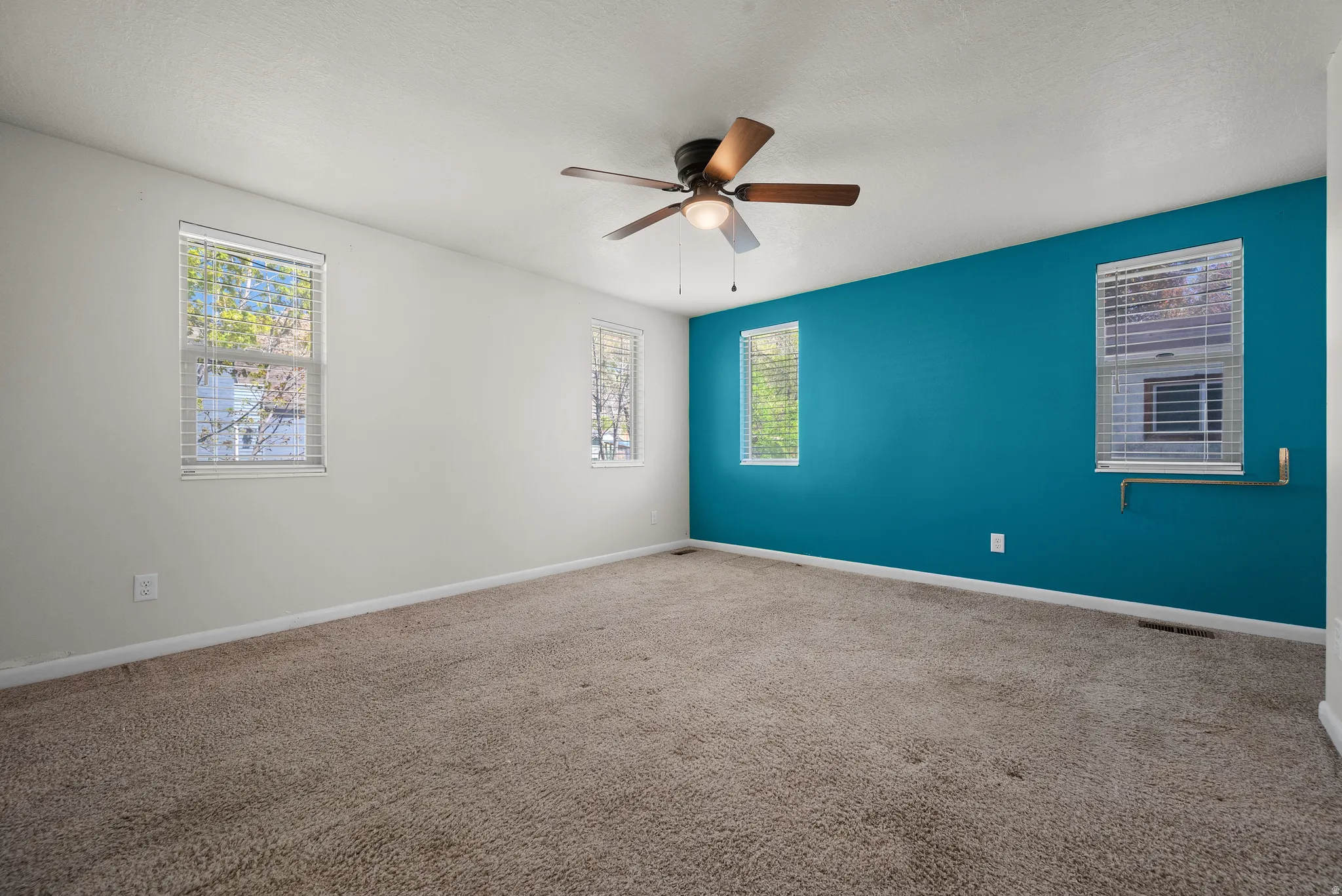 Carpeted empty room featuring ceiling fan and a textured ceiling
