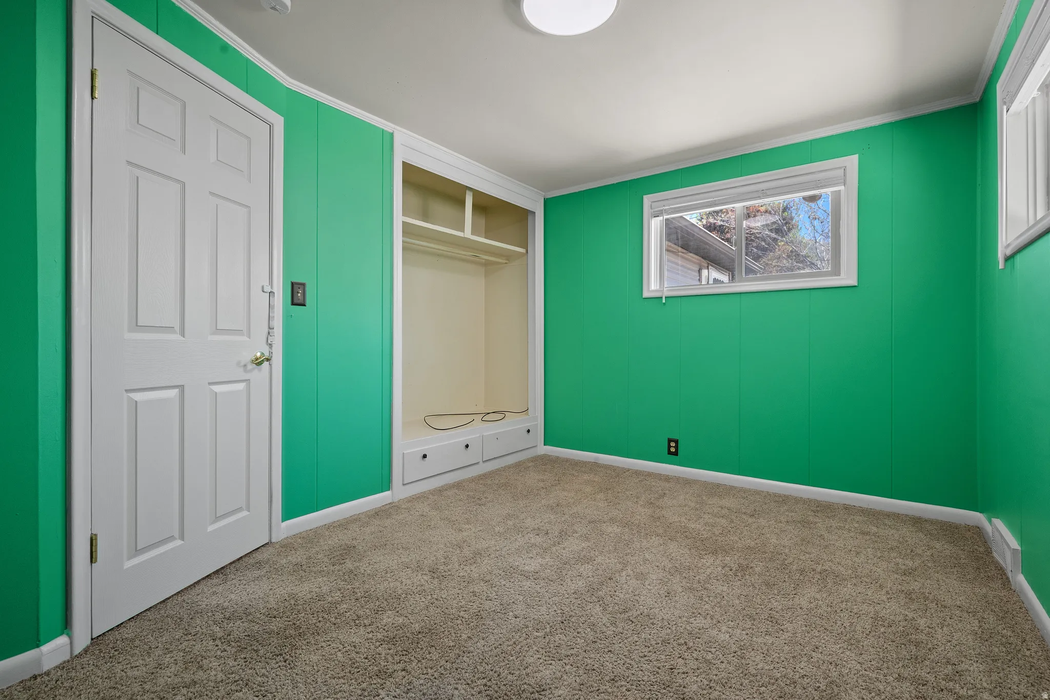 Unfurnished bedroom featuring carpet flooring, ornamental molding, and a closet
