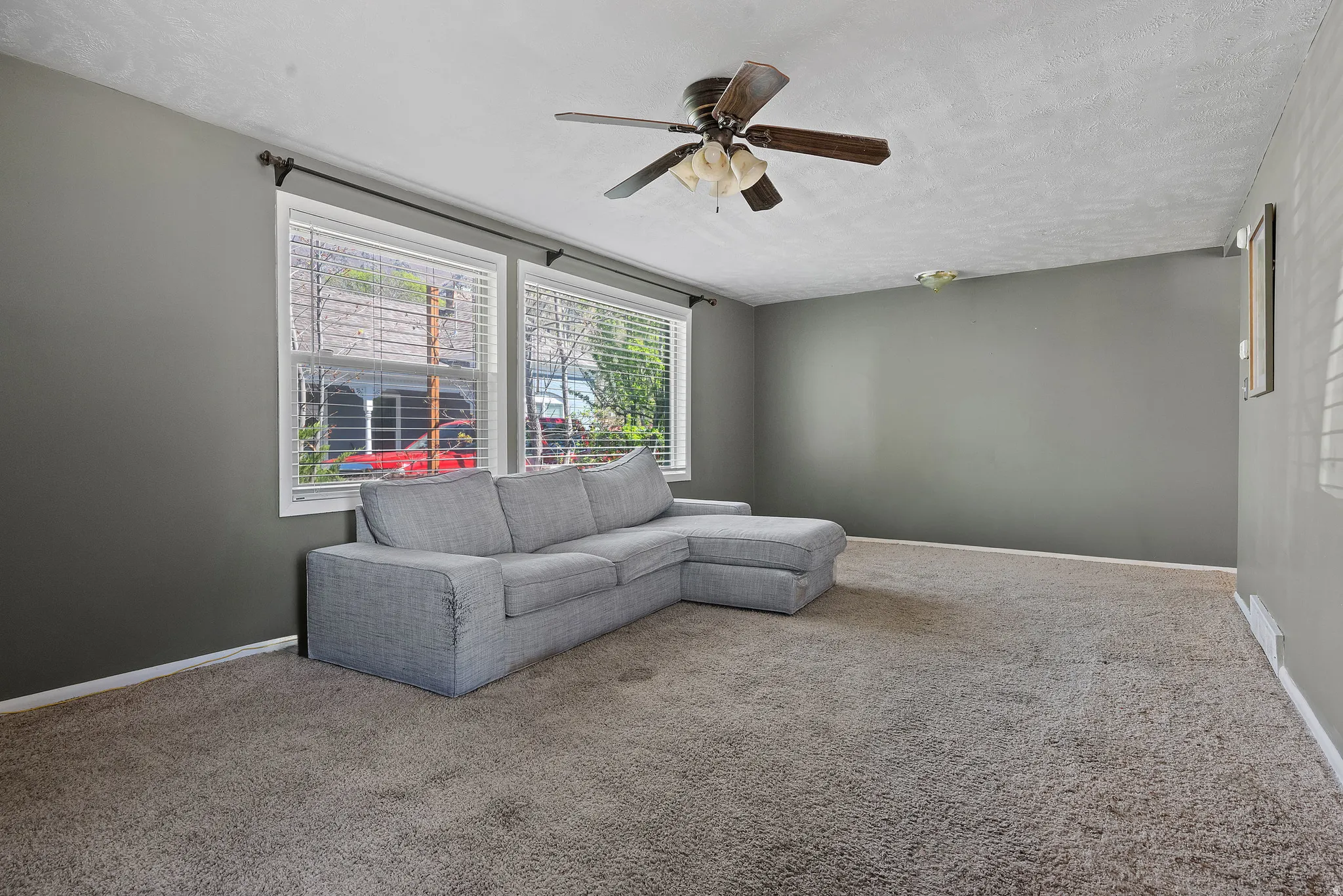 Carpeted living room with a ceiling fan and a textured ceiling