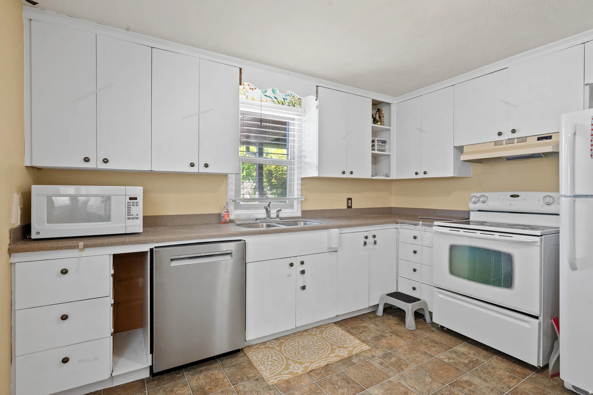 Kitchen with white appliances, open shelves, white cabinetry, and stone finish floors