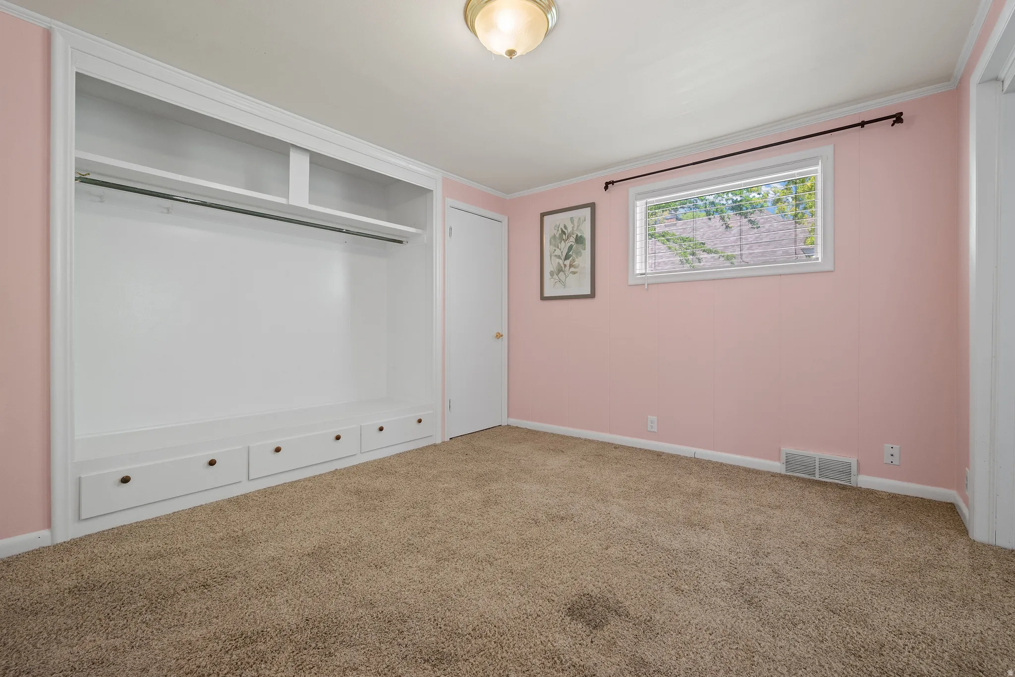 Unfurnished bedroom featuring carpet flooring, crown molding, and a closet