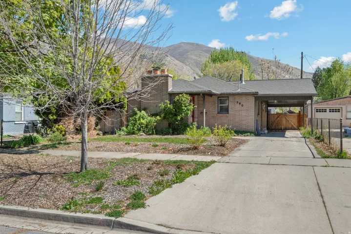 View of front of house with a mountain view, a carport, driveway, brick siding, and a chimney