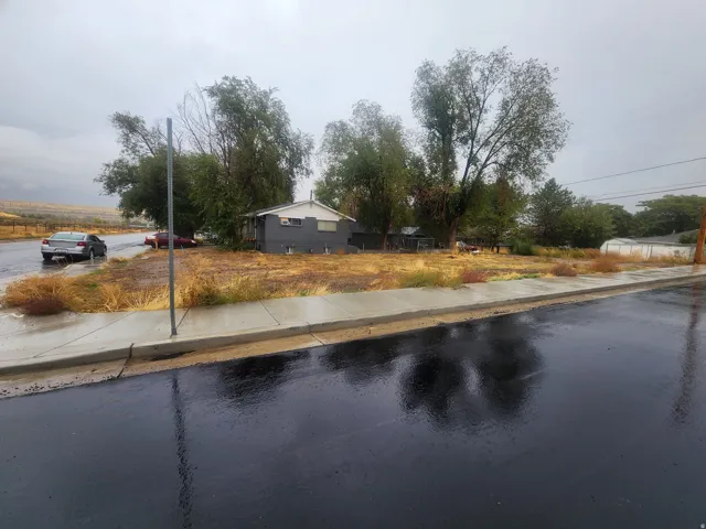 View of asphalt road featuring sidewalks and curbs
