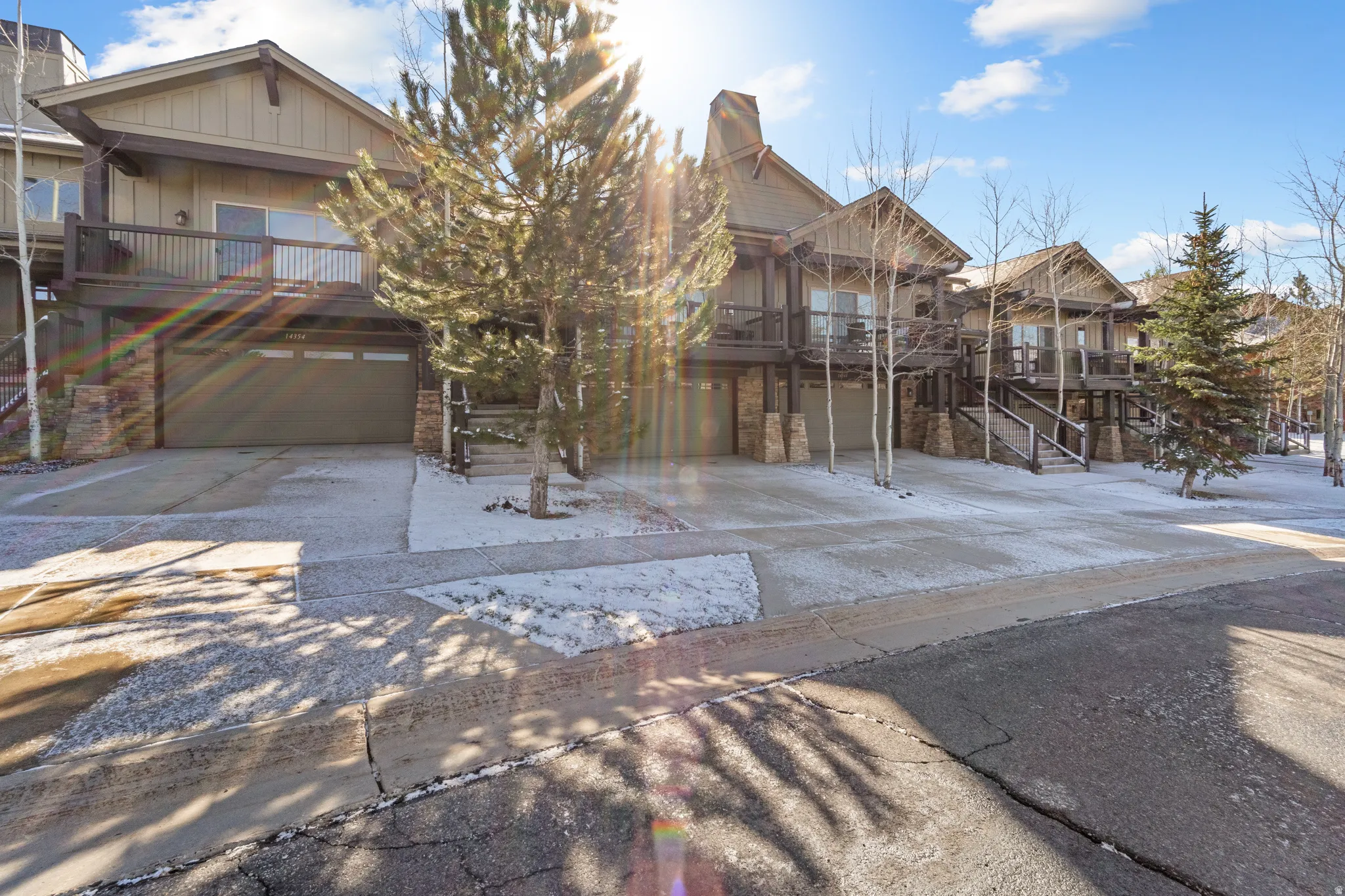 Craftsman-style home featuring driveway, a garage, a residential view, board and batten siding, and stone siding