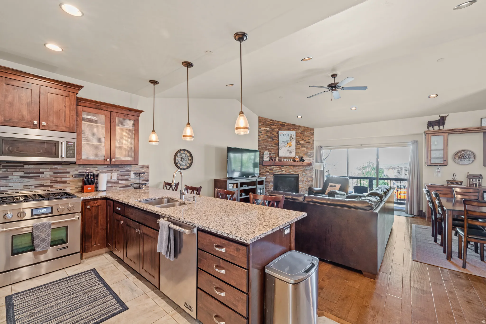 Kitchen featuring stainless steel appliances, light stone counters, a peninsula, a fireplace, and open floor plan