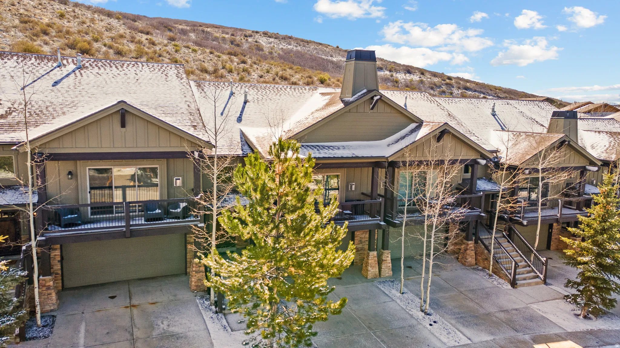 Rear view of house featuring an attached garage, a chimney, concrete driveway, and a mountain view