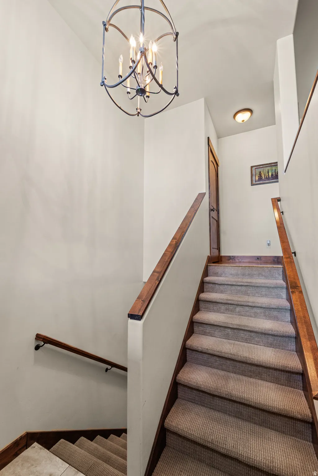 Stairs featuring a chandelier and baseboards