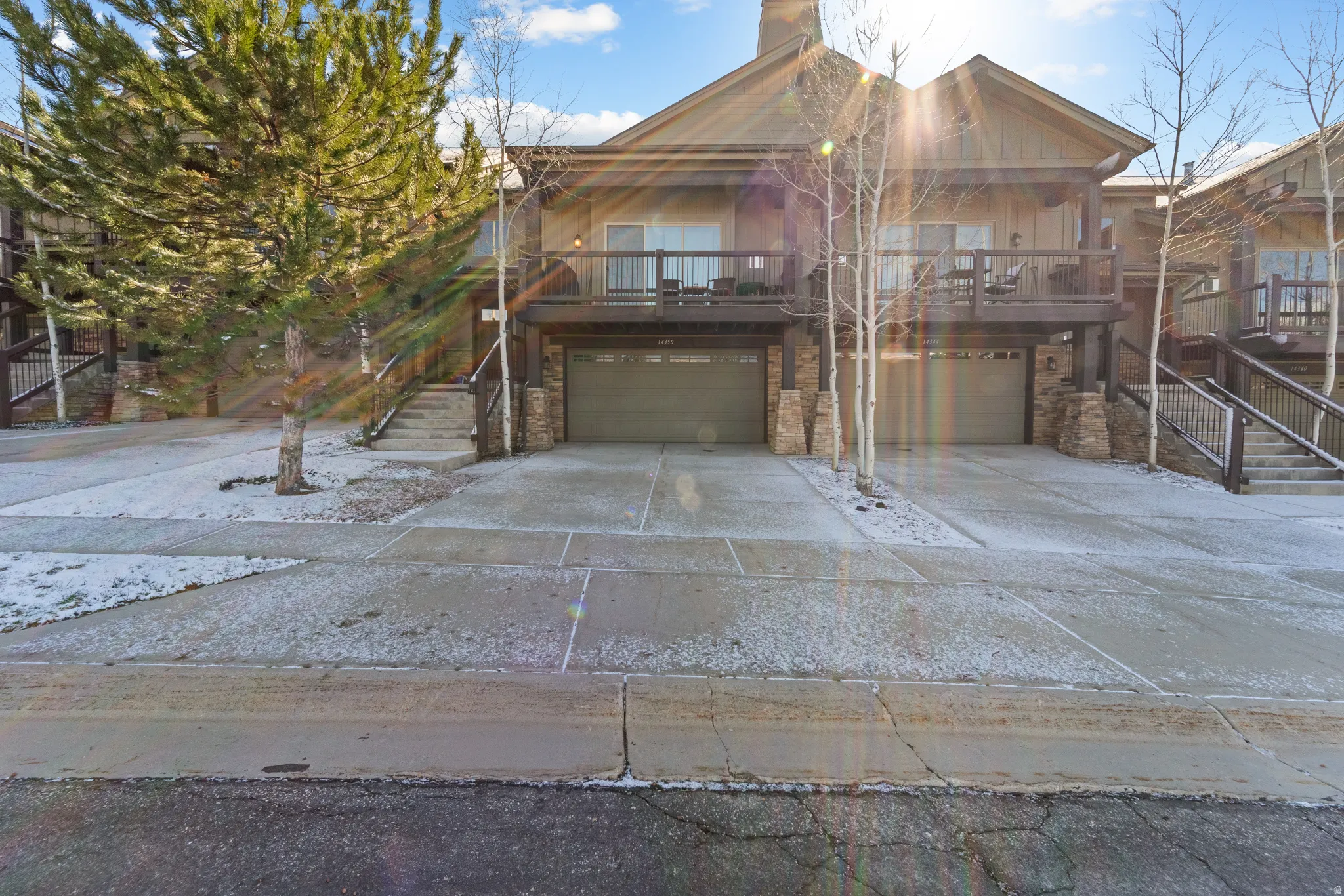 Rustic home with an attached garage, a deck, concrete driveway, and stone siding