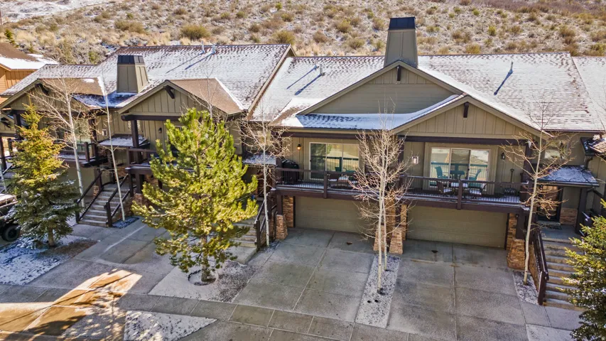 Back of property with a garage, a wooden deck, driveway, a chimney, and a desert view