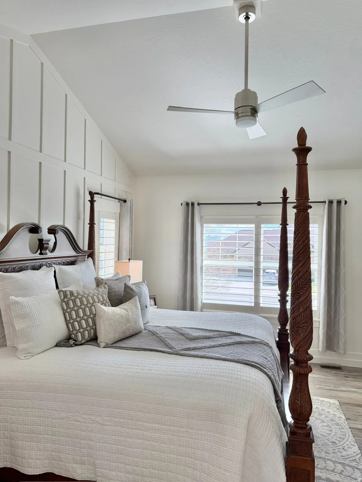 Bedroom featuring lofted ceiling, light wood-type flooring, multiple windows, a ceiling fan, and a decorative wall