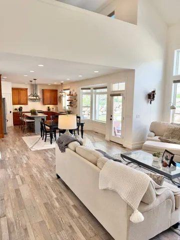 Living room with light wood-type flooring, recessed lighting, and a high ceiling