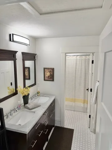 Full bath with double vanity, a textured ceiling, and a shower with shower curtain