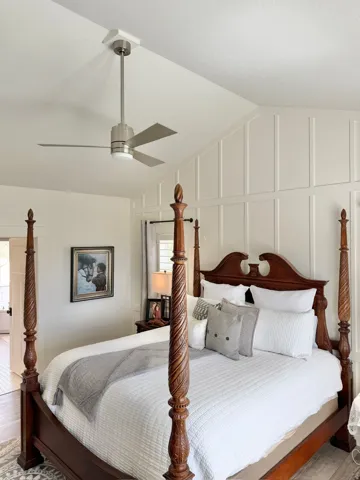 Bedroom with lofted ceiling, a decorative wall, ceiling fan, and wood finished floors