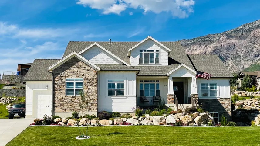Craftsman inspired home with stone siding, board and batten siding, a shingled roof, and a front lawn