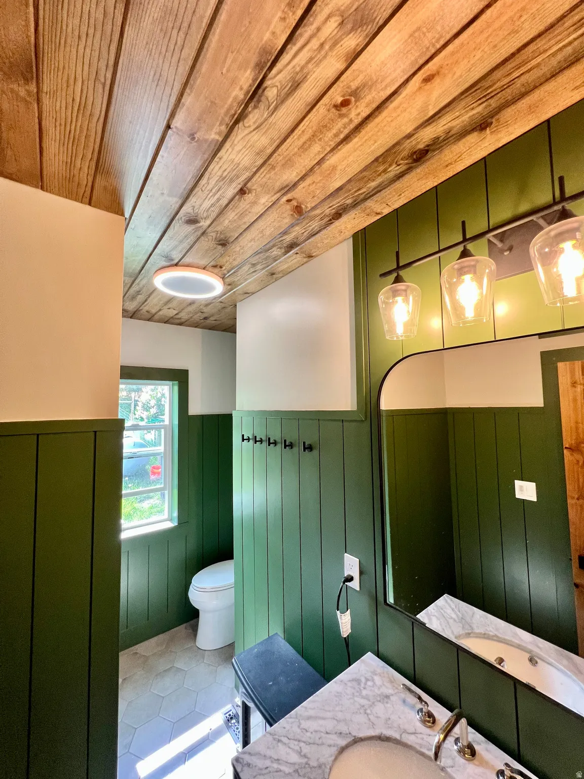 Bathroom featuring a wainscoted wall, vanity, wooden ceiling, wooden walls, and tile patterned flooring