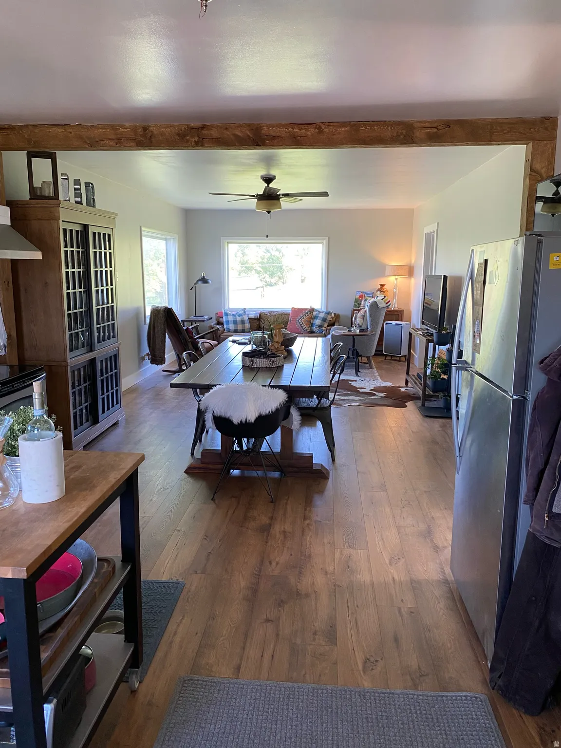 Living room with dark wood-style flooring, ceiling fan, and beam ceiling