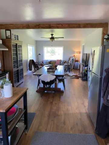 Living room with dark wood-style flooring, ceiling fan, and beam ceiling