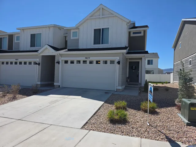 View of front of property with board and batten siding, a garage, and driveway