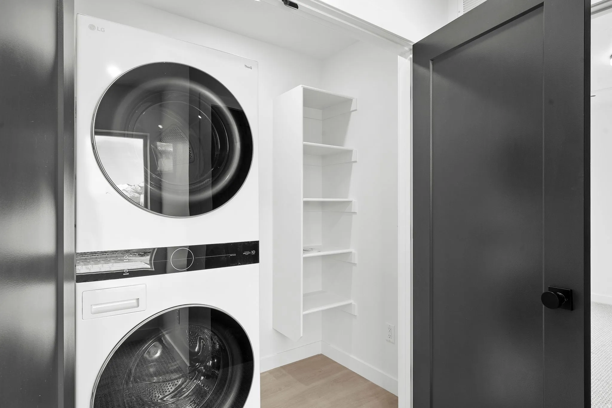 Laundry area featuring stacked washer / drying machine and light wood-style floors