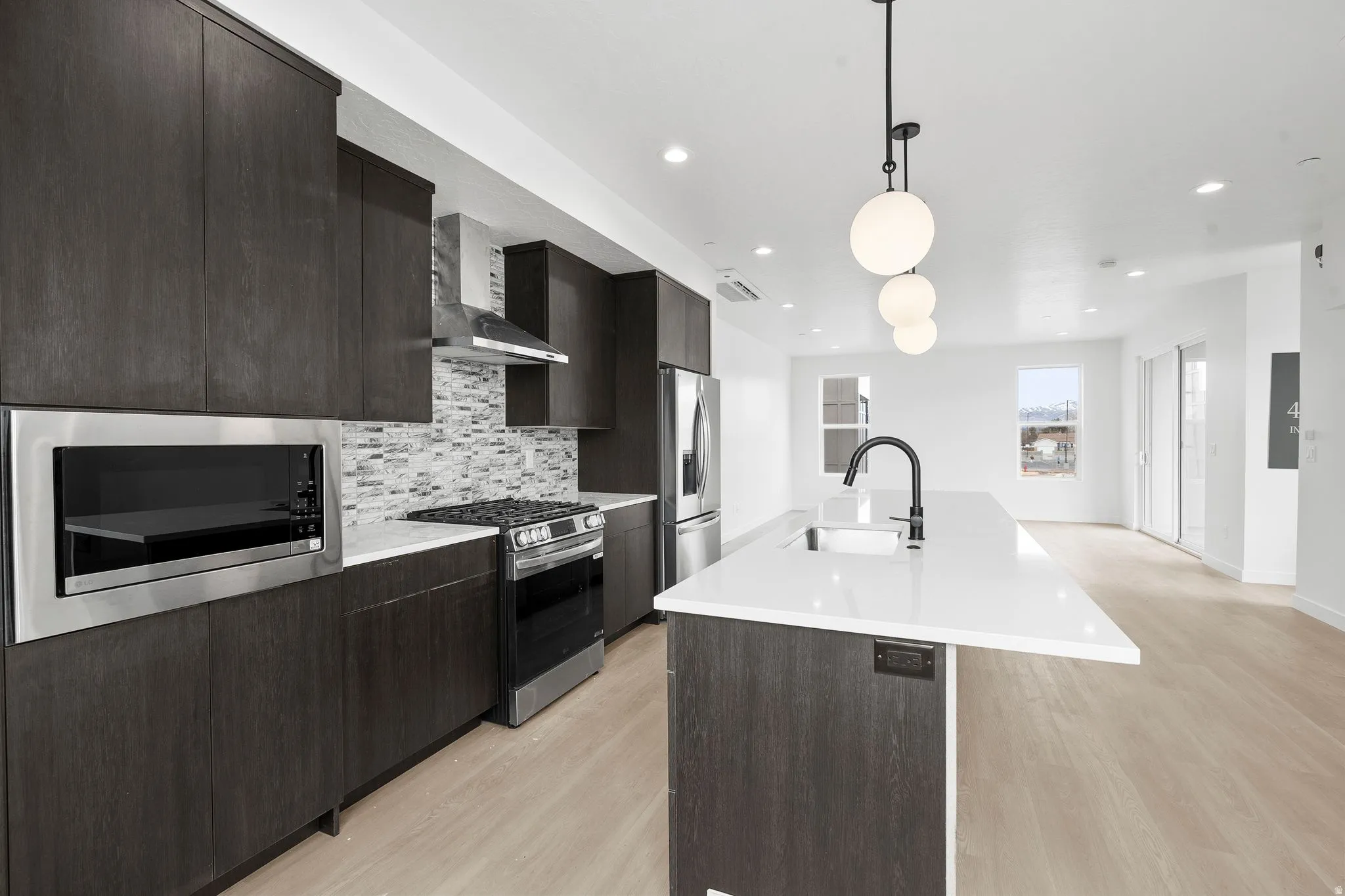 Kitchen featuring an island with sink, stainless steel appliances, and dark wood finish cabinetry