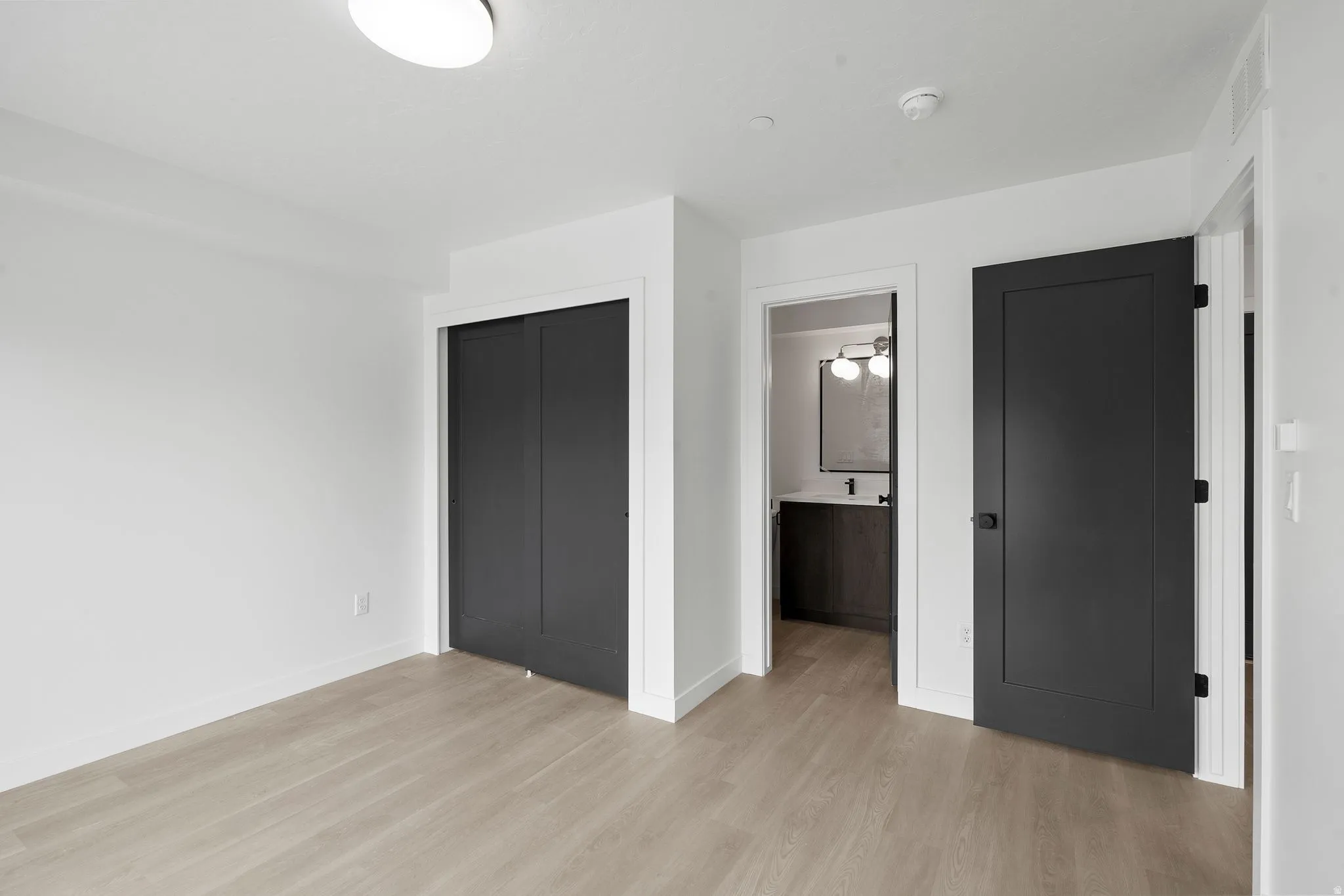 Unfurnished bedroom featuring light wood-type flooring, a closet, and connected bathroom