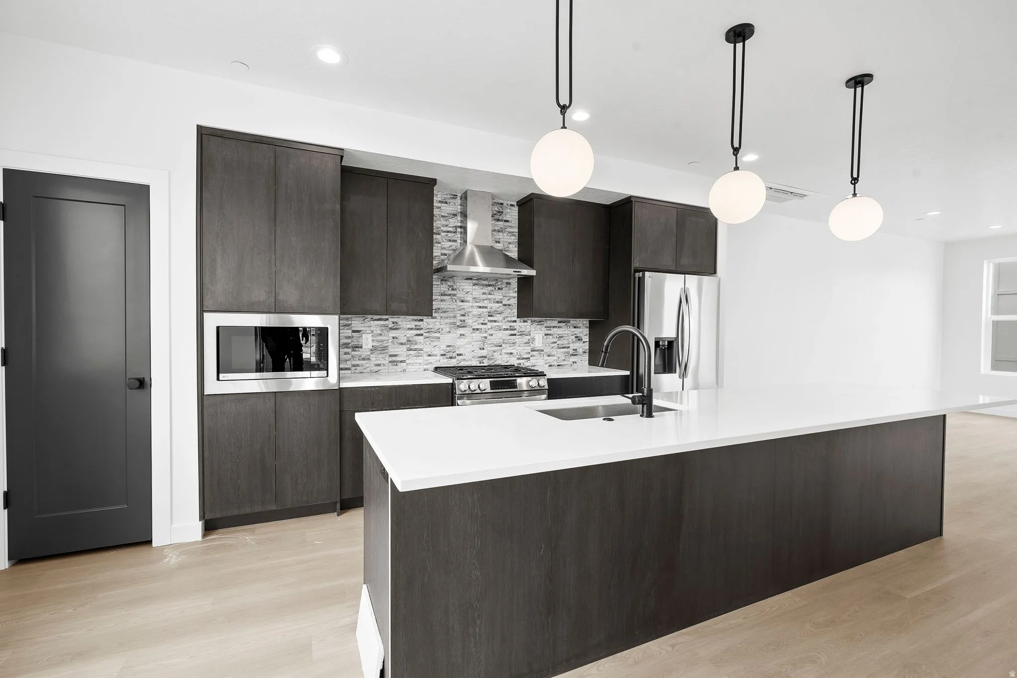 Kitchen featuring dark wood finish cabinets, decorative light fixtures, and stainless steel appliances