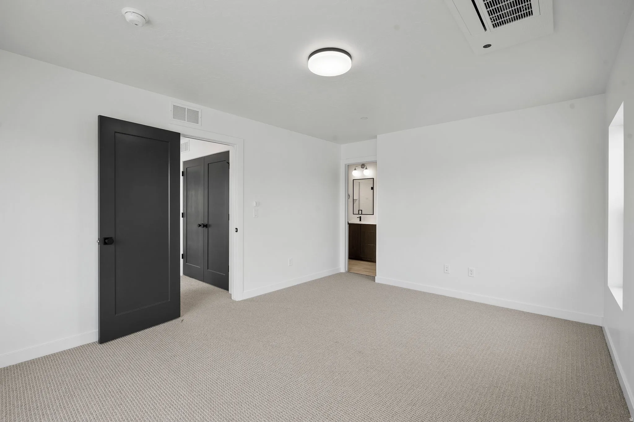 Unfurnished bedroom with light carpet and ensuite bath
