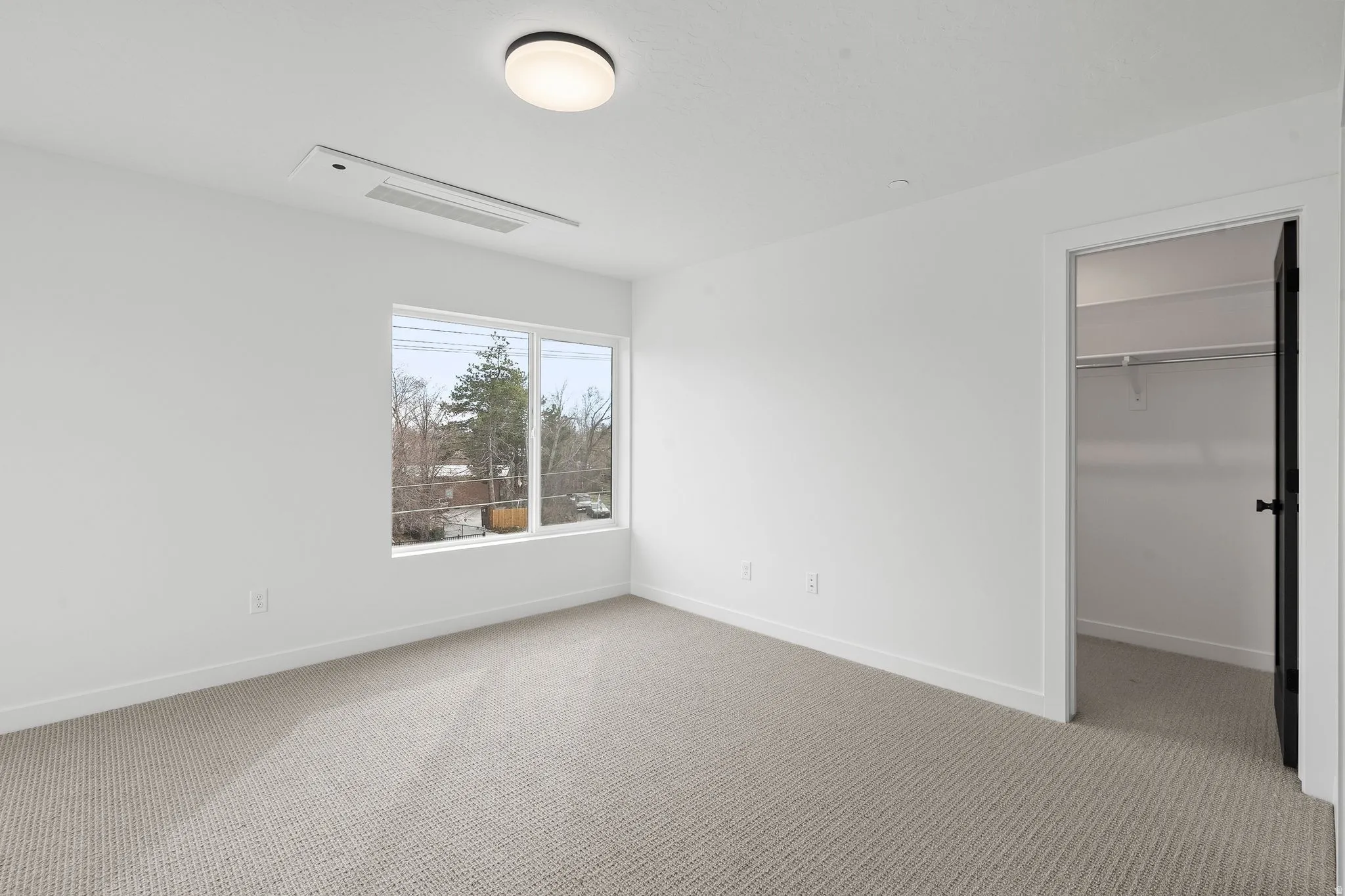 Unfurnished bedroom featuring a walk in closet and light colored carpet